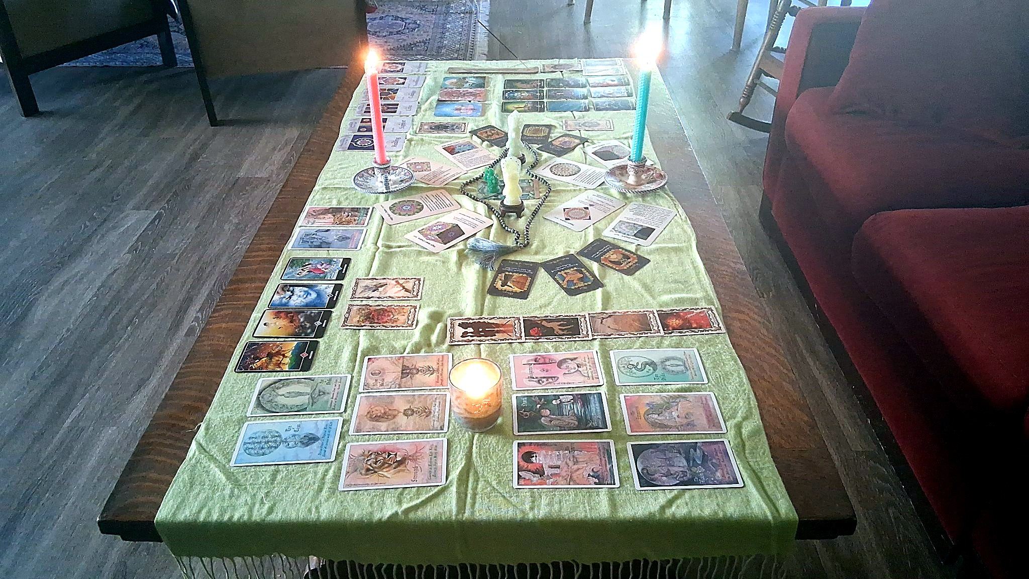 Christine's altar table with lit candles and cards arranged along a green cloth