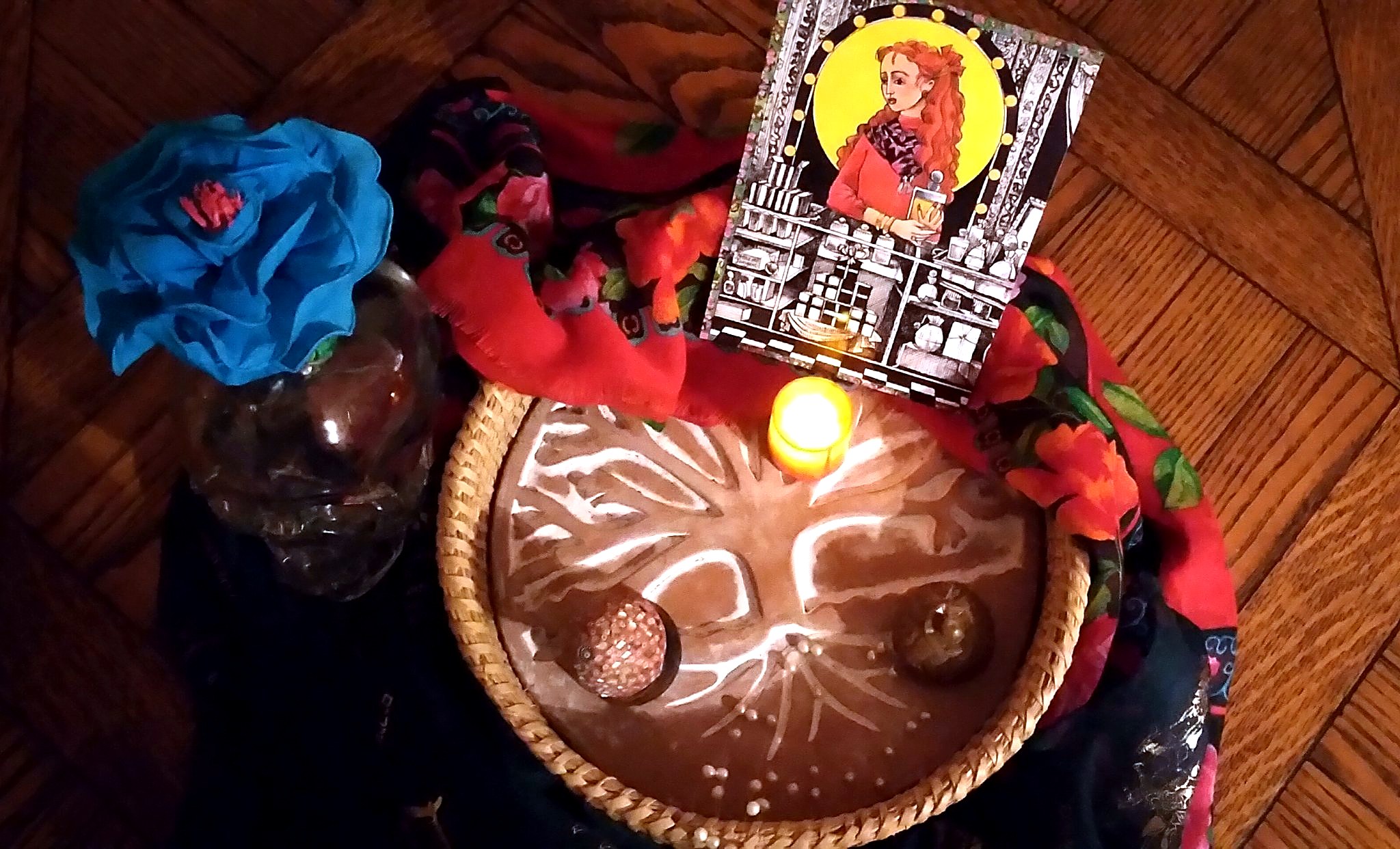 Christine's healing ritual tray seen from above, with a carved tree of life plate, a lit candle and offerings