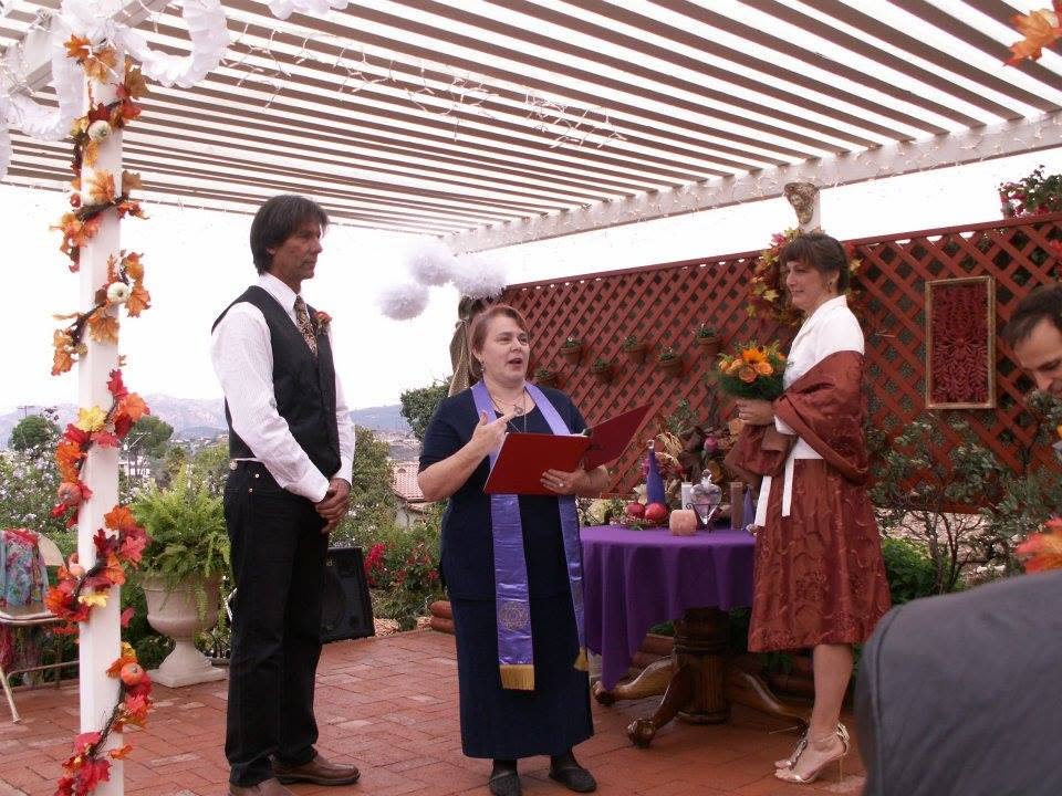 An outdoor wedding ceremony with a pergola and fall garlands