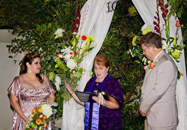 Rev. Christine officiating under a white floral arch