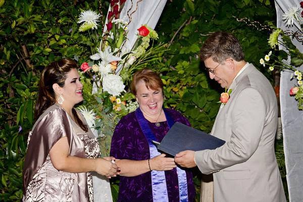 Rev. Christine laughing with a couple during their wedding ceremony